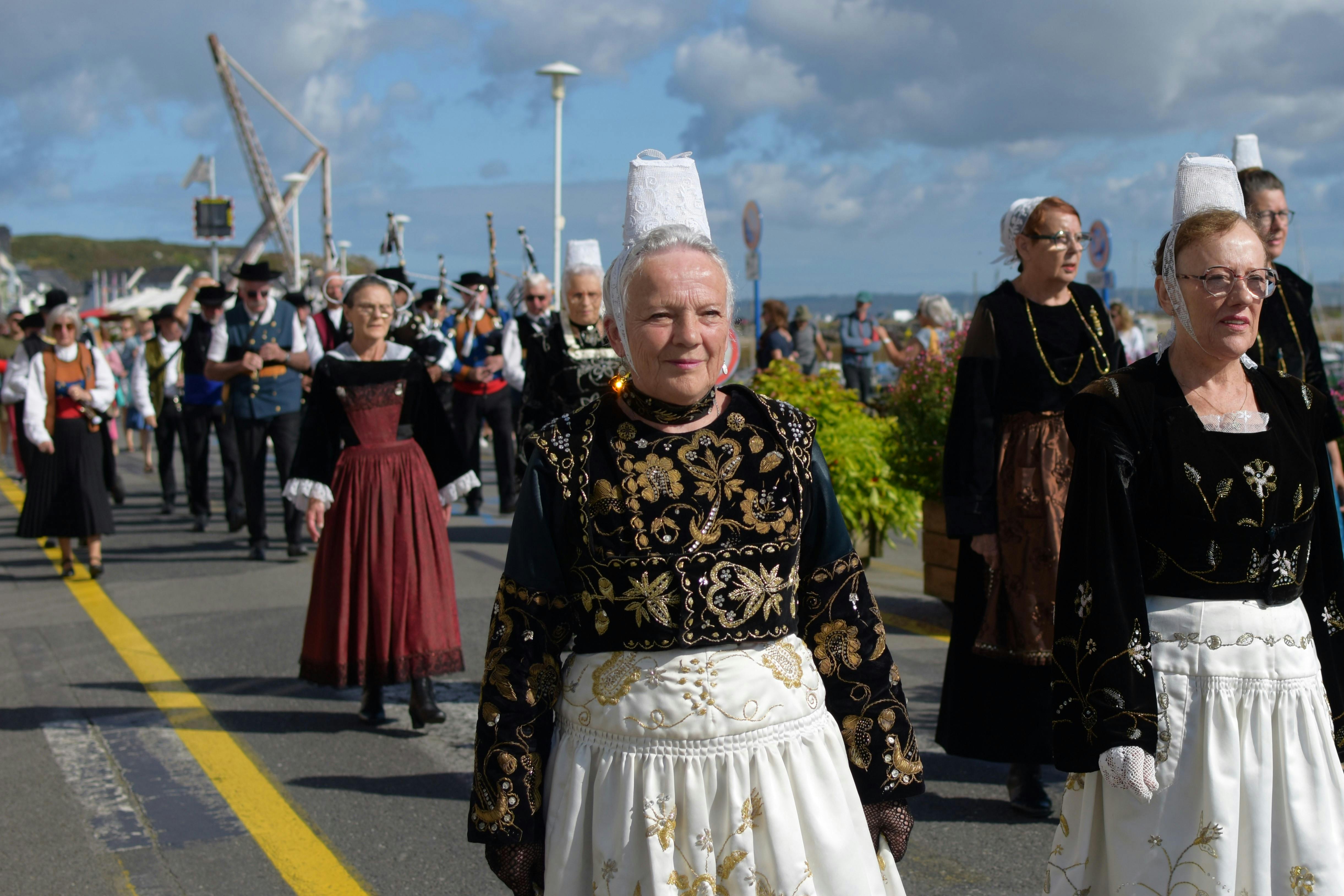 Un groupe de femme et d'homme en costume traditionnel d&eacute;bout les uns aupr&egrave;s des autres